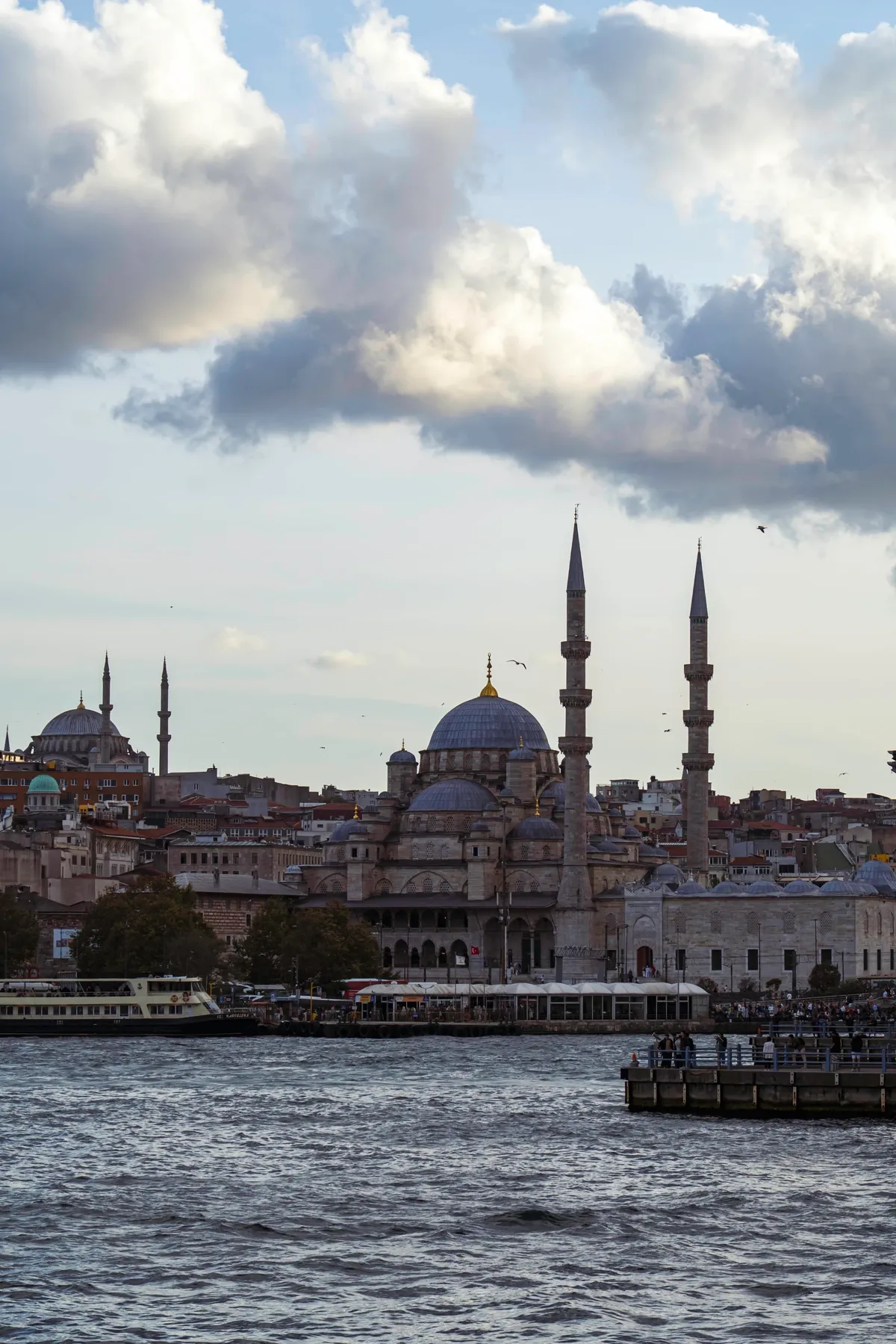 A mosque with a large dome and two tall minarets on the Golden Horn waterfront in Istanbul.