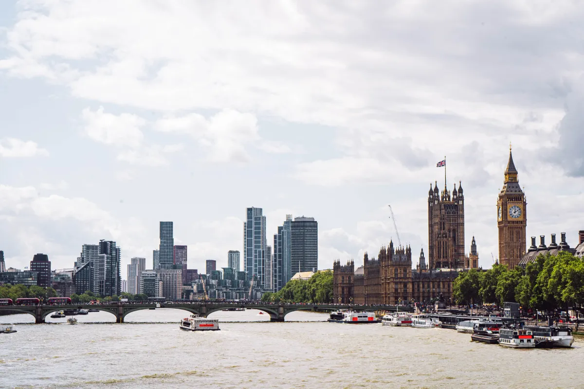 The Thames in London with the Houses of Parliament and Big Ben at right, and glass towers at left.