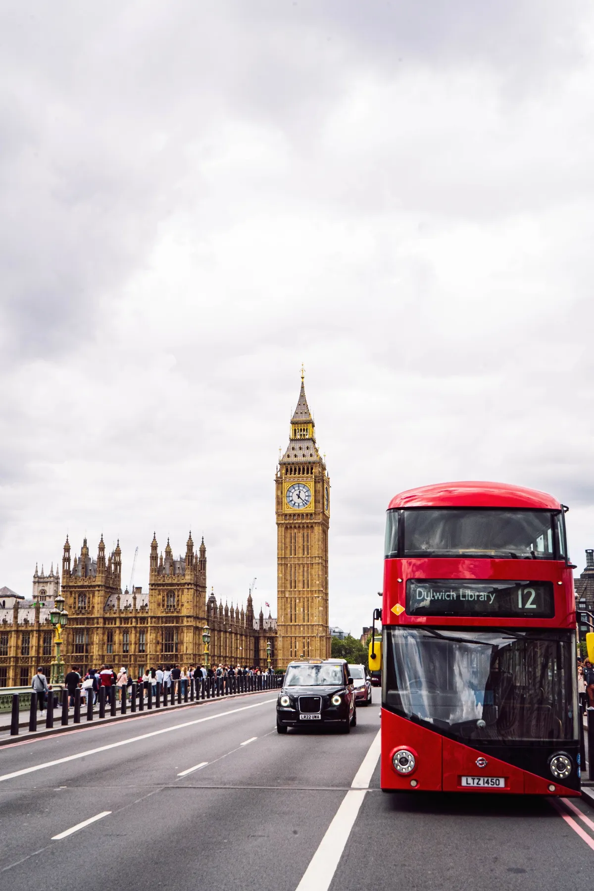 A red double-decker bus and a black taxi on a London bridge, with Big Ben and Parliament behind.