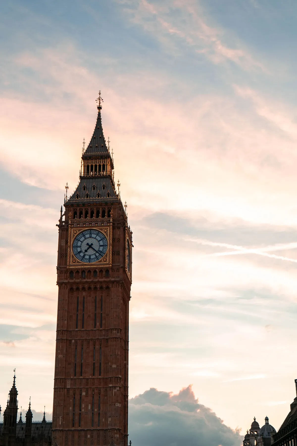The Big Ben clock tower silhouetted against a soft pink and blue evening sky in London.